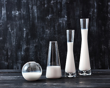 带乳制品牛奶的眼镜站黑色背景上的黑色木桌上,天然机乳制品天然机乳制品牛奶璃瓶中的保存技术,同形状的图片