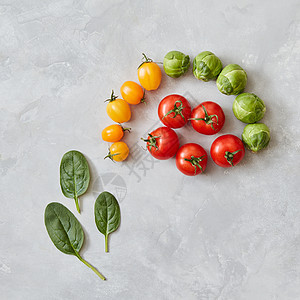 红色黄色西红柿绿色菠菜叶片灰色背景上的成俯视图,平躺西红柿菠菜叶图片