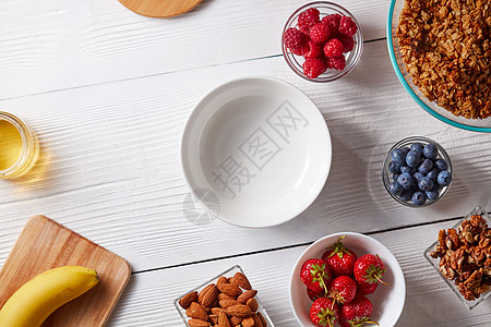 健康早餐的原料麦片,坚果,覆盆子,草莓,蓝莓白色木制背景的碗里顶部视图,健康早餐配料碗燕麦麦片新鲜浆图片