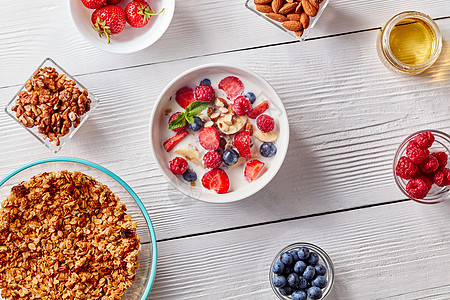 白色桌子上的白色陶瓷碗,带天然机成分,用于天然健康早餐自然健康饮食的平躺自制的麦片放盘子里,香蕉切片,浆果,图片