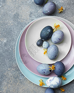 复活节蓝色鸡蛋个彩色的餐盘上,石头背景上花蓝色复活节彩蛋图片