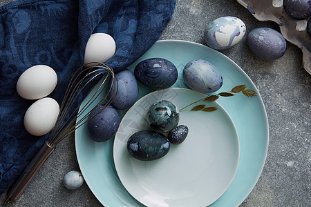 复活节鸡蛋盘子上,布绿色植物石头背景上用蓝布烤复活节彩蛋图片