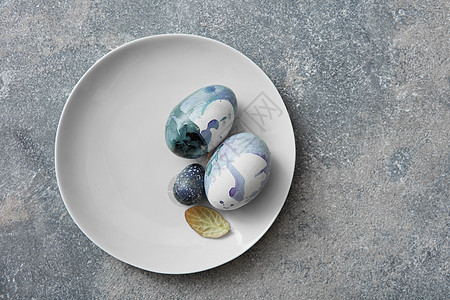 石头背景上的盘子上的蓝色复活节彩蛋彩绘复活节彩蛋图片