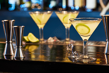 冰冷鸡尾酒马提尼杯与切片石灰酒吧桌子上酒吧里美味的鸡尾酒背景图片