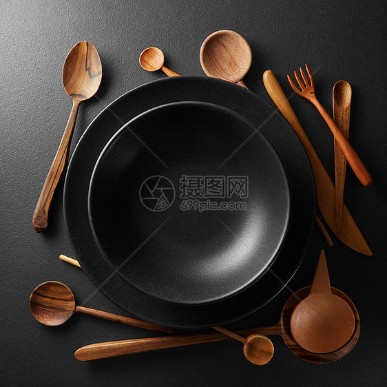 黑色桌子上的黑色盘子木勺子叉子刀盘子木制餐具图片