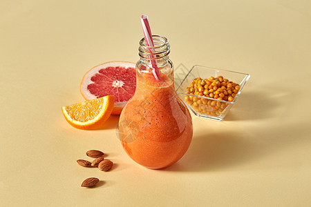 新鲜冰沙与胡萝卜,橙色,葡萄柚,杏仁沙棘个璃纸橙色背景维生素饮料的橙色冰沙与柑橘,胡萝卜,沙棘杏仁橙色的纸图片