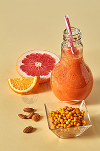 混合柑橘汁葡萄柚,橘子,沙棘杏仁纸背景维生素饮食饮料橙色柑橘饮料与沙棘杏仁璃上的橙色纸背景图片