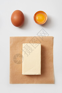 白色背景下的生鸡蛋纸上黄油块的顶部视图黄油鸡蛋图片