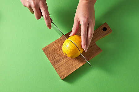 柑橘类水果柠檬,用于准备自制的健康排饮料,用于绿色背景的木板上进行饮食自然健康饮食的位女士的手绿色背图片
