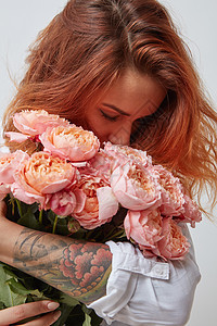 漂亮的红发女孩,手臂上纹身,着粉红色的玫瑰,情人节,母亲节漂亮的女孩着粉红色的玫瑰图片