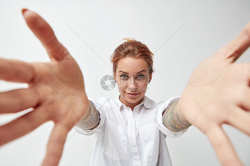 可爱的红头发女人张开双臂表示欢迎轻的女人微笑着双臂张开白色的背景