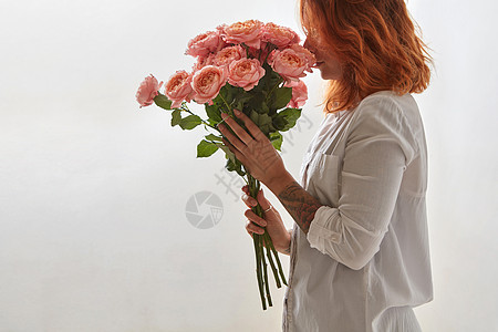 粉红色的玫瑰由个红头发的轻女孩灰色背景上手中,瓦伦丁节红亮的女孩着粉红色的玫瑰灰图片