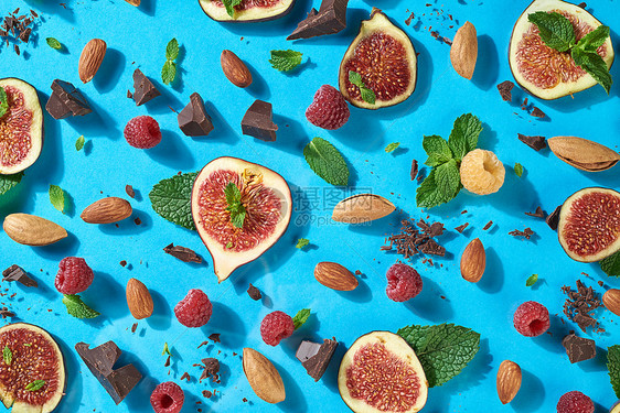 美味的甜甜点模式,成熟的无花果,坚果,巧克力,新鲜的覆盆子,叶子的意思蓝色的背景自然成分的能量健康饮食顶级景观夏季图图片