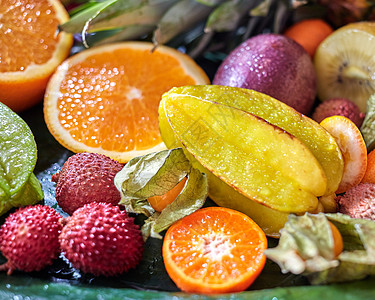 辛辣的新鲜热带水果后备西番莲,杨桃,荔枝,金橘,橙色半片,绿叶上的剑麻特写镜头顶部景观新鲜多汁的热带水果图片