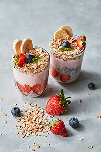 新鲜的天然机成分,用于烹饪健康早餐自制的麦片,半的草莓,辣椒种子,蓝莓酸奶个灰色的石头桌子上的眼镜,文字的地方自制图片