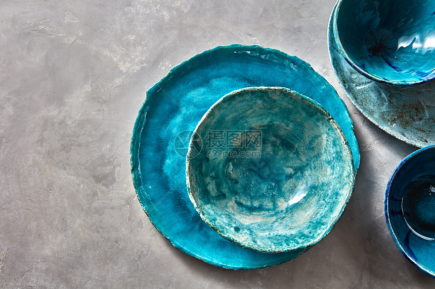 装饰陶器碗,盘子覆盖灰色背景上的釉,文字的地方传统手工制作的顶部视图灰色桌子上的瓷蓝色碗盘子五颜六色的陶瓷复古手工图片