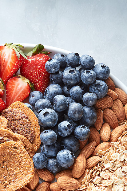 健康早餐的天然成分草莓蓝莓杏仁坚果燕麦自制麦片灰色石桌上的薯片新鲜成熟的水果蓝莓杏仁坚果燕麦片灰色图片