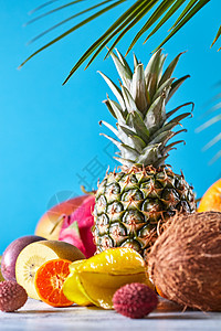 菠萝,芒果,火龙果,西番莲,椰子,杨桃,金橘异国水果与热带树叶蓝色的背景,地点为文字素食健康异国情调的热带水果图片