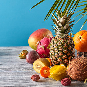 群异国情调的热带水果芒果,火龙果,西番莲,椰子,菠萝,杨桃,金橘蓝色背景上素食健康来自成熟水果的异国图片