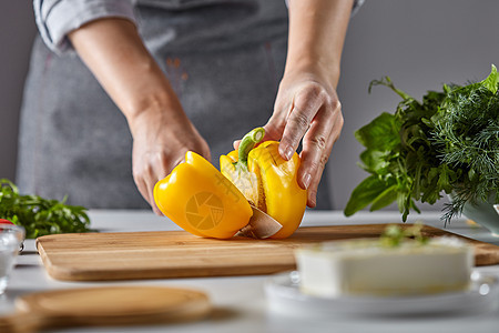 女家庭主妇厨房的桌子上用蔬菜奶酪切黄胡椒沙拉步步地饭女人的手厨房桌子上的木板上切黄胡椒烹饪沙拉图片