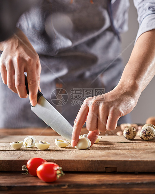 个穿着围裙的女人张旧木桌上的木板上切鹌鹑蛋步步的饮食沙拉穿着灰色围裙的厨师木板上切煮鹌鹑蛋步步地饭图片