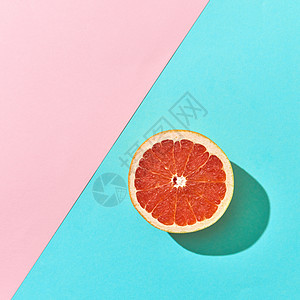 半个成熟的葡萄柚个双粉红色蓝色纸板背景下,的文字柑橘类水果的风景多汁的半柑橘葡萄柚蓝色粉红色纸板图片