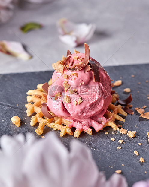 勺浆果冰淇淋晶片上,巧克力片石板板上,灰色的混凝土桌子上装饰着花瓣花甜食冰淇淋水果勺与巧克力片晶片石板板上的灰图片