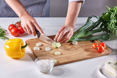 女人的手厨房桌子上的木板上用各种新鲜蔬菜切绿韭菜步步的沙拉烹饪新鲜的韭菜片切成位女厨师的手,厨房桌子上的木板上图片