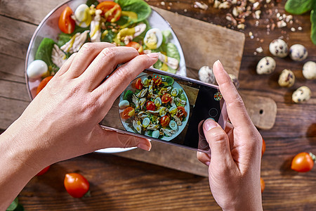 厨房的桌子上,木板上,盘自制的沙拉女人用手机拍沙拉的照片女孩用手机拍沙拉的照片食物博客的的风景图片