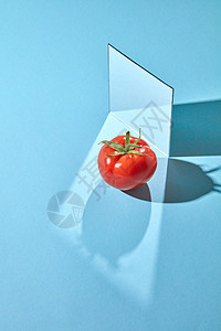 红色番茄,绿色茎镜子蓝色背景与阴影个间隔的副本创造的食物成分镜子成熟的番茄蓝色背景上的构图,反射阴影复图片
