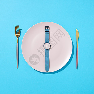 手表与时间6orsquo时钟个白色的盘子上,刀叉蓝色的背景上,放置文本限制食物摄入减肥的平躺白色盘子与图片
