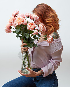 个纹身的女人,着大粉红色玫瑰,放个璃花瓶里,背景灰色的,母亲节礼物红发女孩,纹身美丽的粉红图片