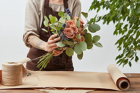 花店工作场所女的手正安排个新的花与玫瑰,装饰绿叶个轻的背景步供文字用的地方轻女子花店正用鲜花玫瑰图片