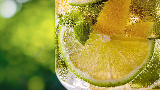 夏季碳酸冷鲜饮料与片柠檬石灰,薄荷叶璃上的绿叶模糊的背景含酒精含酒精的夏季饮料柑橘柠檬水夏季饮料绿图片