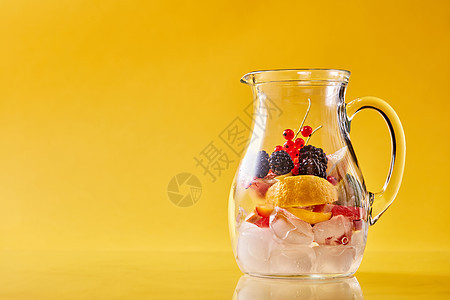 准备自制的清爽冷果冲床璃罐上的黄色背景,寒冷的非酒精夏季饮料的璃罐与柑橘,浆果冰背景图片