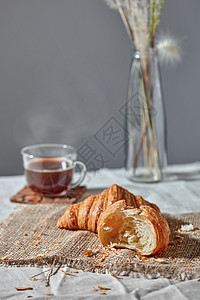 新鲜烘焙的自制牛角包与包屑纺品与热芳香咖啡灰色纺品背景文字的位置欧式早餐早晨早餐,新鲜牛角包咖啡杯,灰图片