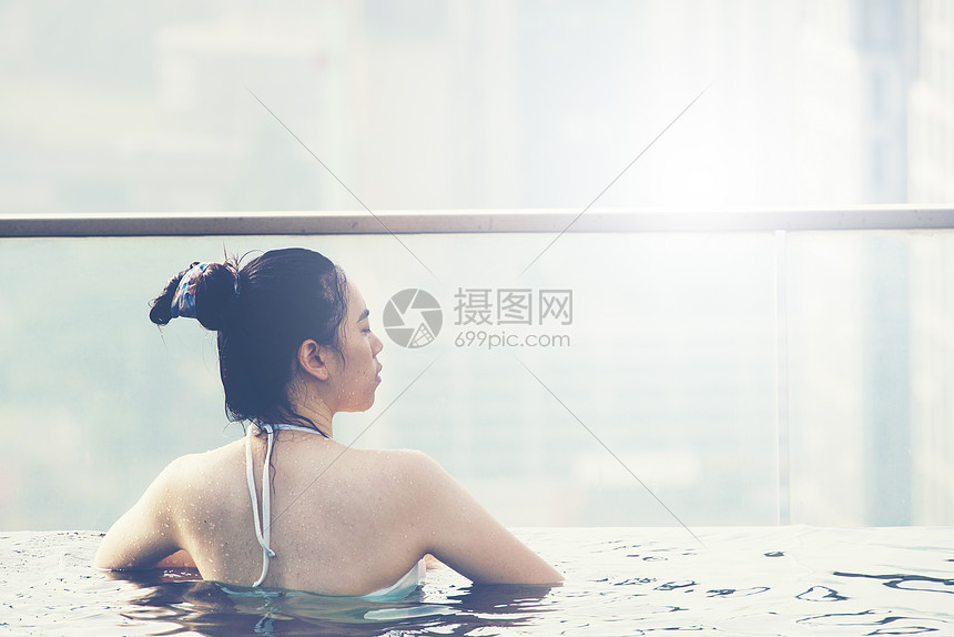 轻女子屋顶游泳池与美丽的城市景观,阳光老式过滤图像图片