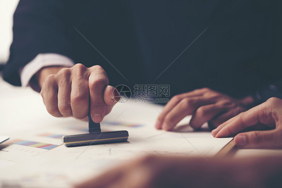 个人的特写,办公桌上的文件上加盖批准的印章图片
