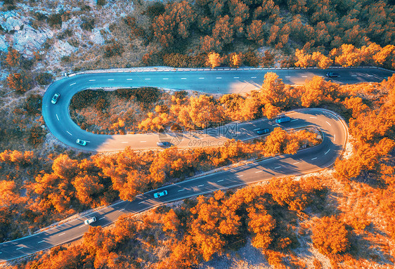 秋林中蜿蜒道路的鸟瞰图,日落山上美丽的沥青道路橘子树的顶部景色公路秋天穿过林地欧洲旅行五颜六色的风景图片