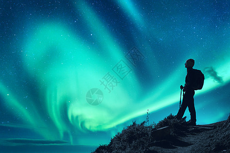 北极光夜间背着背包的女人的轮廓山上的女孩,夜空中北极光天空星星北极光徒步旅行明亮的极光人的景观图片