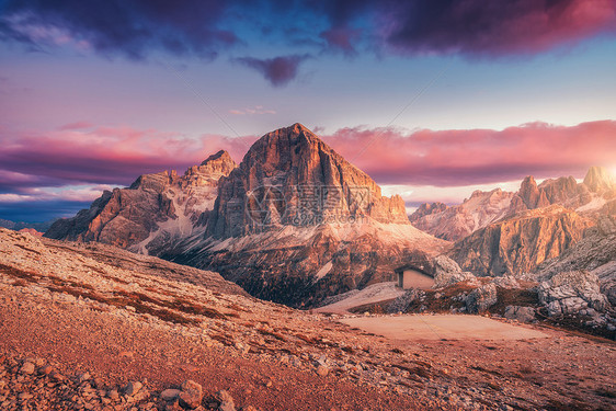 意大利白云石日落时的山脉风景与高岩石,石径,小房子,蓝天与粉红色的云彩晚上秋天的风景与山谷意大利阿尔卑斯山黄昏图片