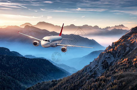 飞机夏天五彩缤纷的日落时,雾中飞过群山风景与客机,小山低云,蓝天白色飞机商务旅行商业飞机空中视野图片