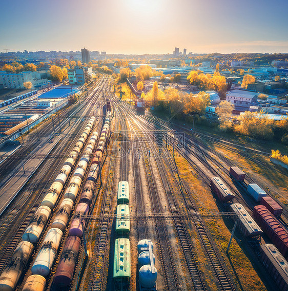 秋季日落时火车站彩色货运列车的鸟瞰图铁路上货物的货车重工业工业场景与货运列车,城市建筑无人机的顶部视图图片