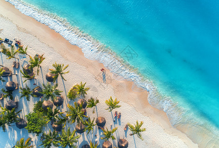鸟瞰雨伞,沙滩上的棕榈,人们,日落时的蓝色大海波浪非洲桑给巴尔的暑假热带景观棕榈树,阳伞,白沙,海洋的风景图片