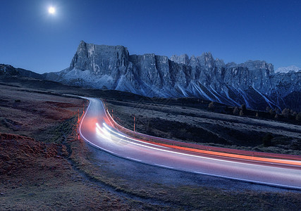 秋天的夜晚,蜿蜒的道路上模糊的汽车前灯风景与沥青路,轻小径,山,蓝天与月光黄昏意大利的巷道月亮公路岩石上图片