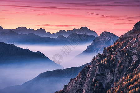 意大利白云石秋天美丽的日落时,雾中的山脉景观与高山山谷,低云,树木山上,红色的天空与云黄昏空中视野帕索贾乌图片