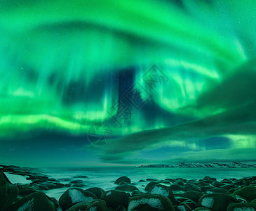 北极光海洋上俄罗斯泰伯卡的北极光星空与极地的灯光云彩夜冬季景观明亮的极光,大海里模糊的水中的雪石旅行图片