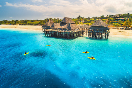 鸟瞰美丽的酒店人皮艇日落夏天桑给巴尔,非洲的风景景观与木制酒店海上,蔚蓝的水,沙滩,绿树,独木舟豪图片