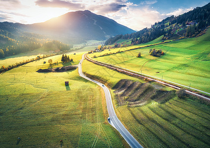 意大利白云岩夏季日落时山谷道路的空中景观沥青道路,铁路,绿色草地的山丘,蓝天,树木,建筑物的顶部景观公路田野图片