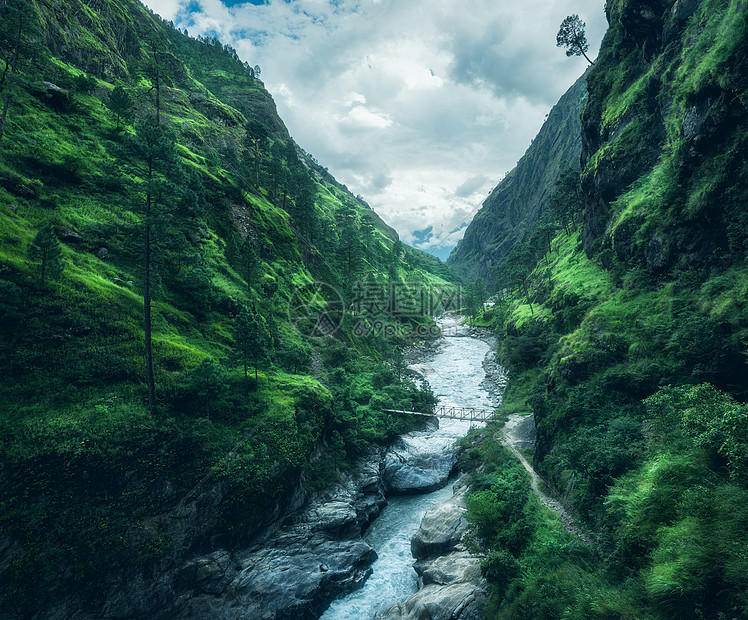 美丽的山覆盖着绿色的草喜怒无常的景观与山谷,河流,瀑布,草地森林,天空与云夏季尼泊尔阴天喜马拉雅山旅行自然图片